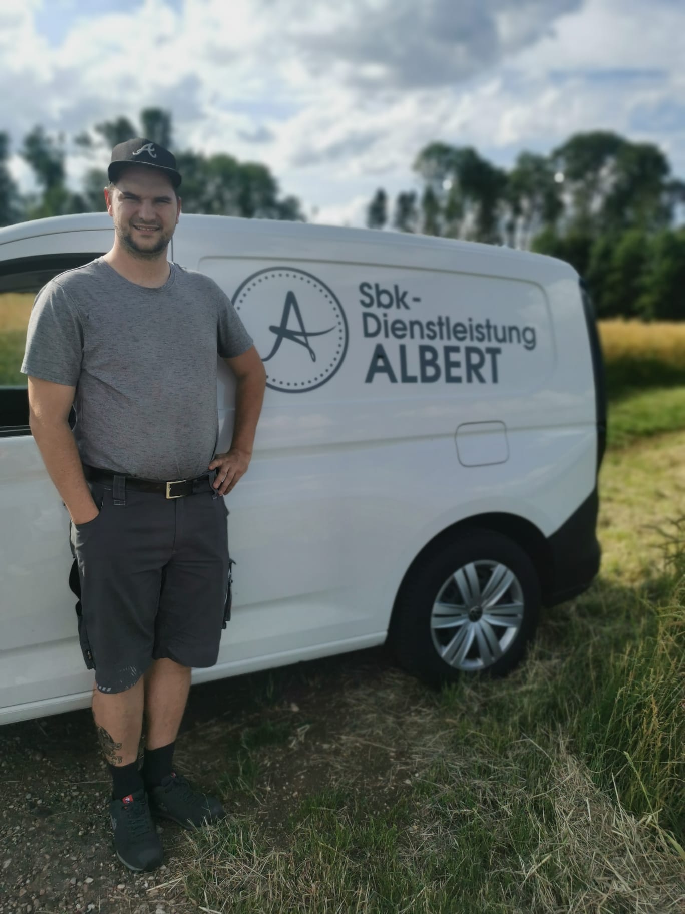Lukas Albert steht in einem grauen T-Shirt vor seinem weissen Lieferwagen mit der grauen Aufschrift SBK-Dienstleistung-Albert